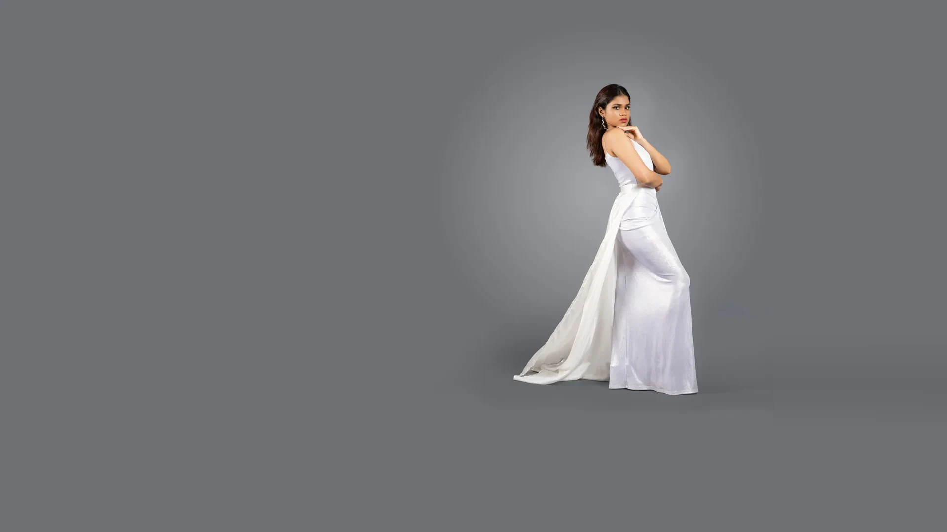 Fashion portrait in a flowing white gown against a grey studio backdrop