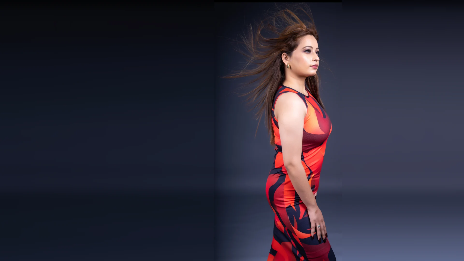 Fashion portrait in a patterned red and orange dress with windswept hair