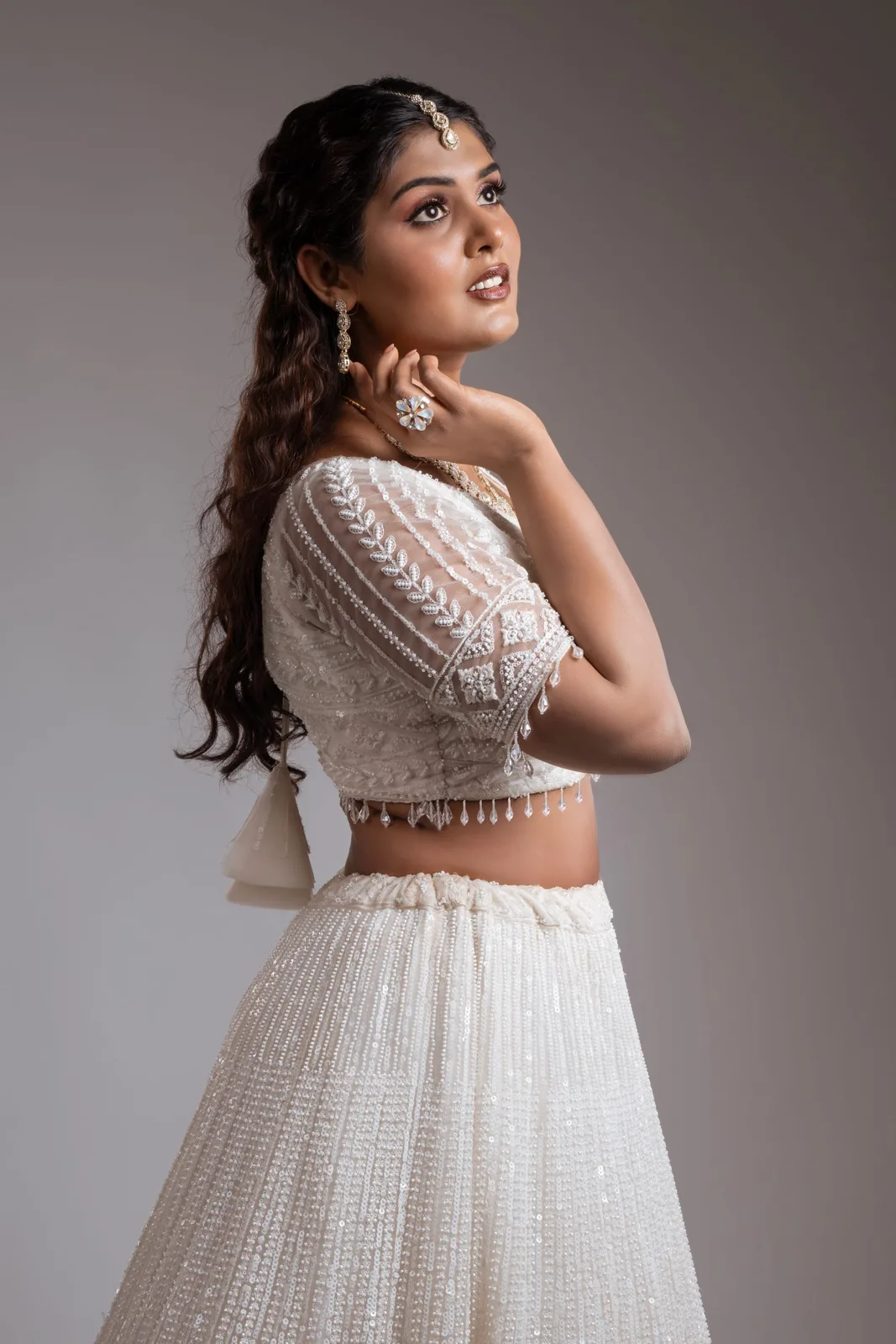 Portrait showcasing a white embroidered blouse, skirt and statement earrings